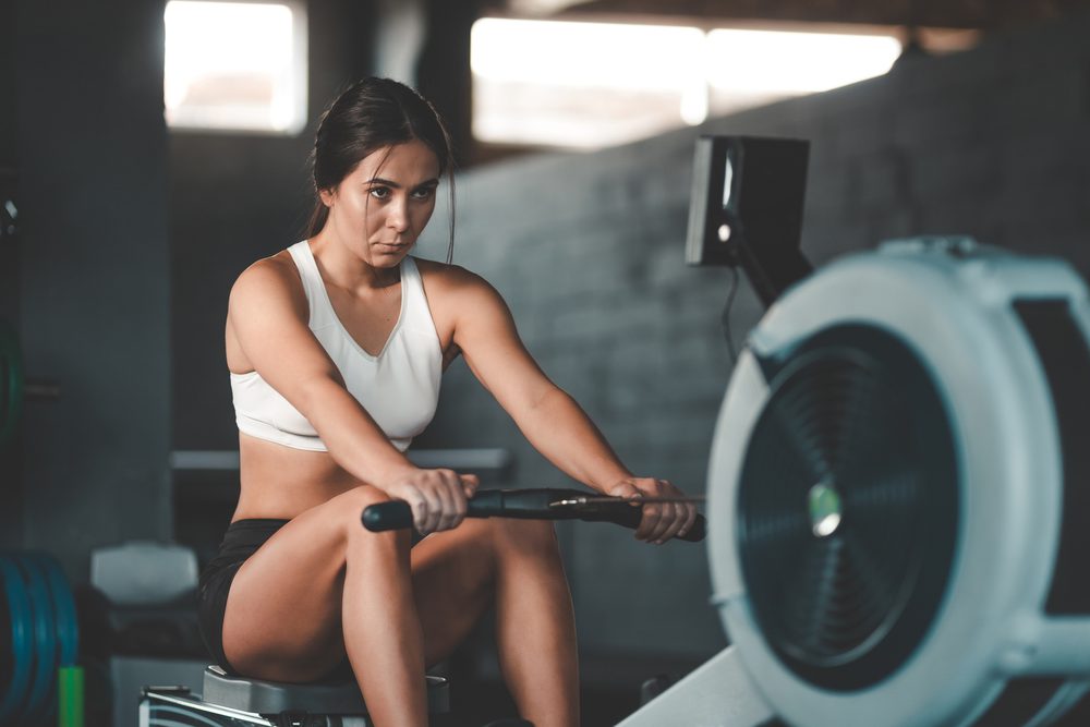 A woman using a rowing machine with focused, controlled form
