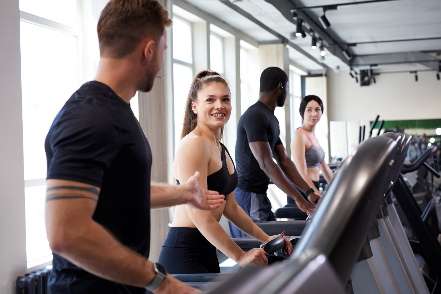 A diverse group of people training together on treadmills and ellipticals in a shared gym space