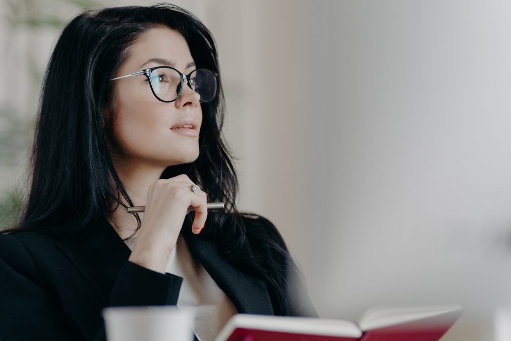 A woman writing in a planner, organizing her priorities for a busy stretch