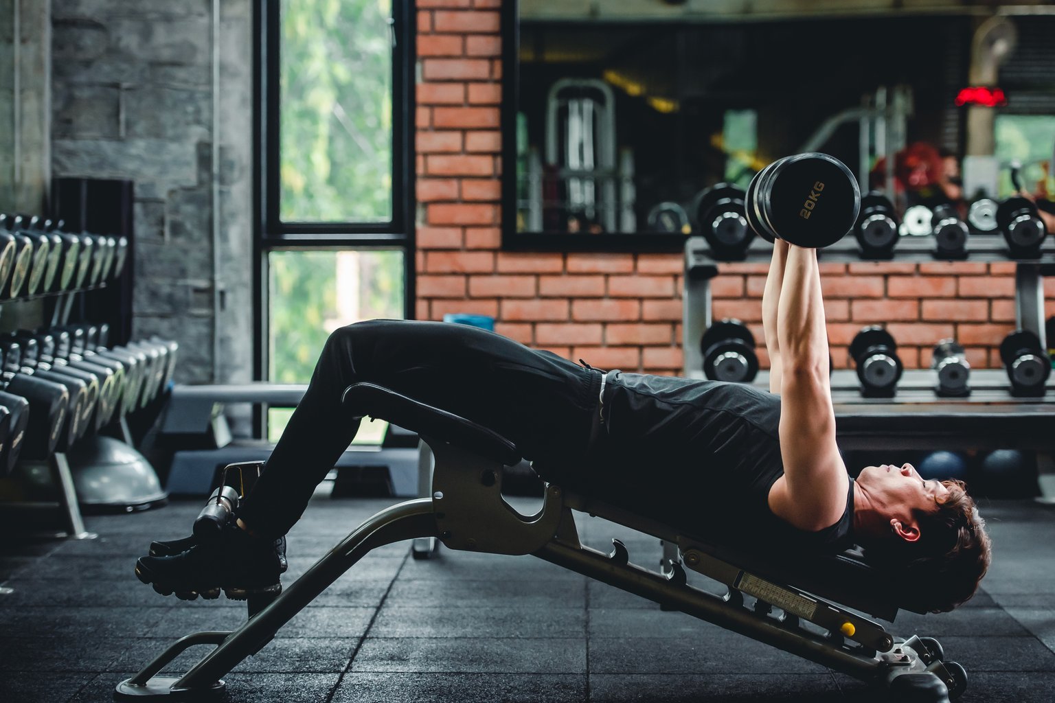 A man performing a dumbbell chest press with controlled form in the gym