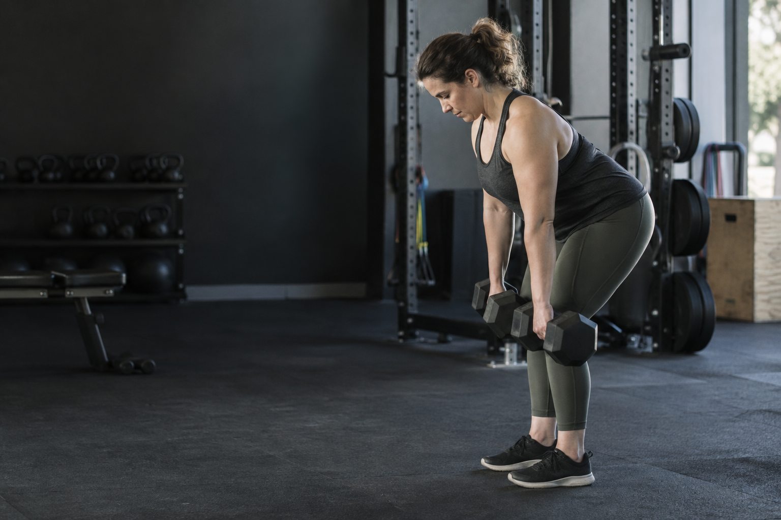 An ordinary adult performs a controlled Romanian deadlift with moderate dumbbells