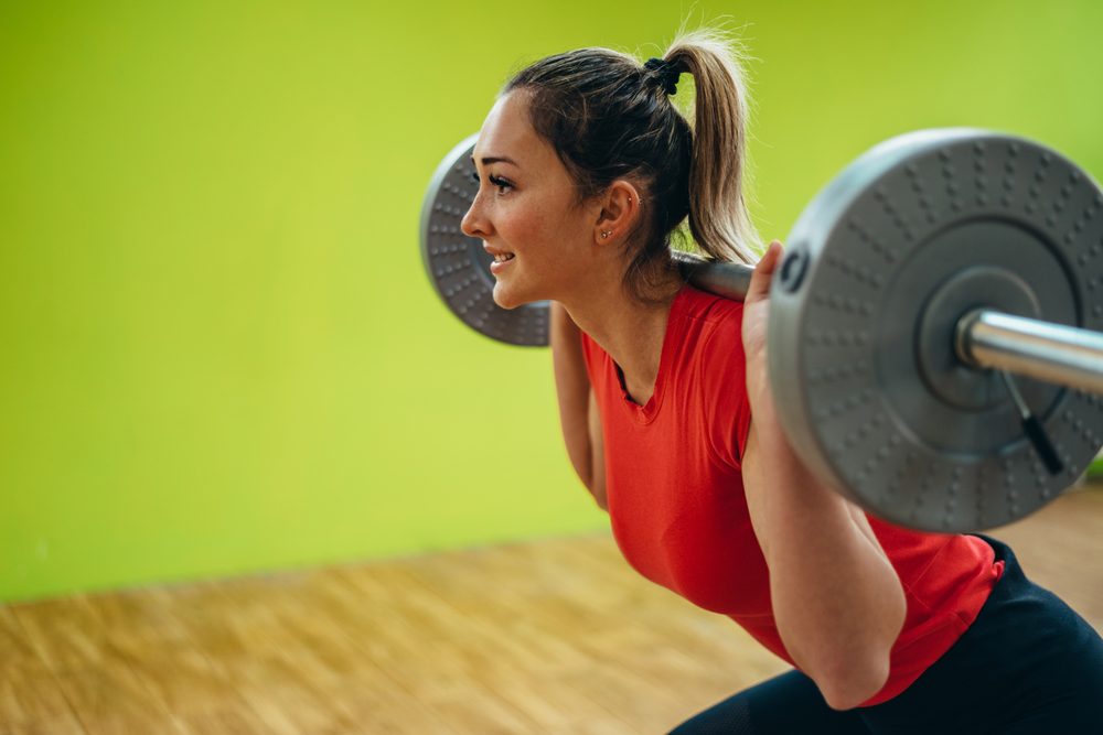 A woman performing a barbell squat with focused form in the gym