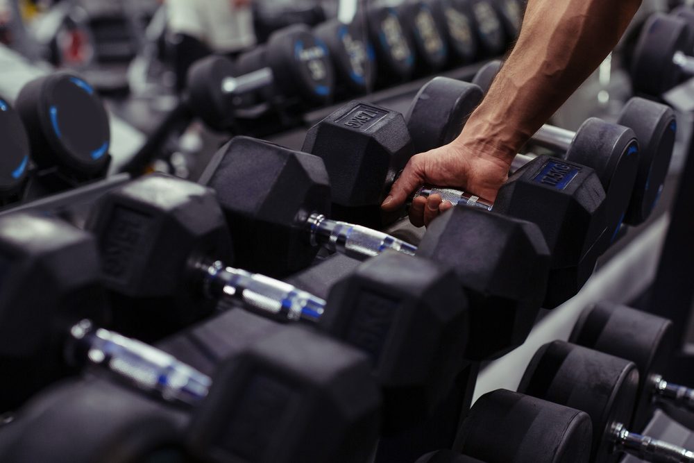 A hand reaching for a dumbbell from a nearby rack during a workout