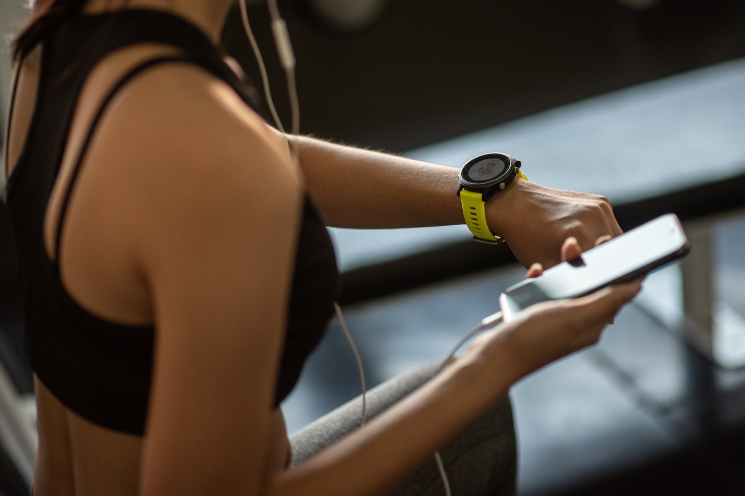 A woman checking her smartwatch during a rest period in the gym