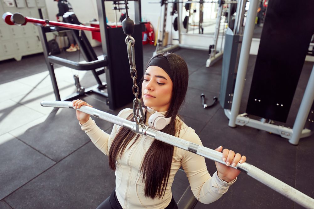 A close-up of a woman gripping the bar during a lat pulldown exercise