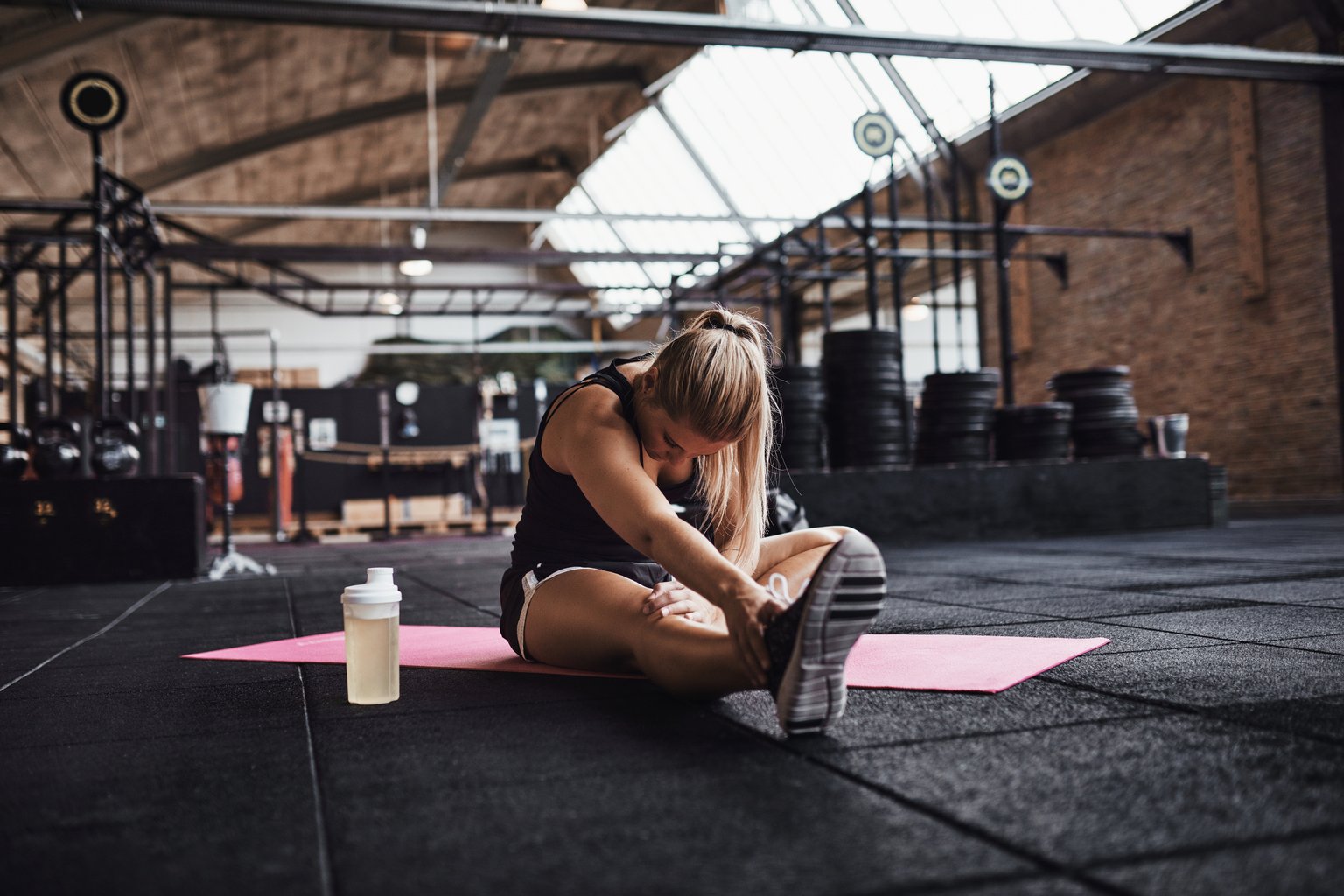 A woman stretching on the gym floor before her workout