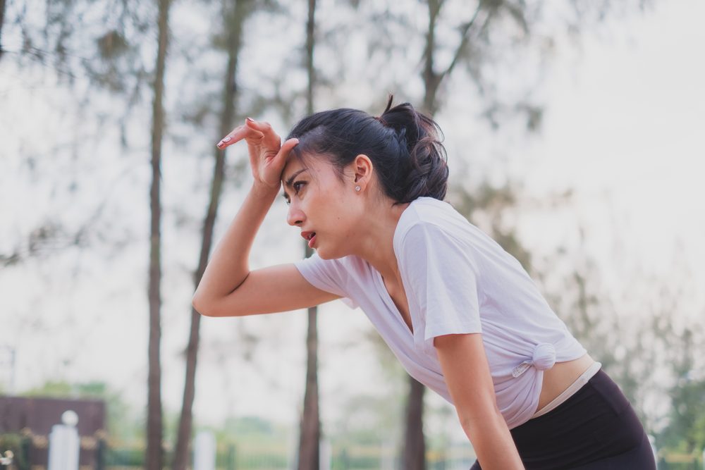 A woman wiping her brow after an outdoor workout, tired but finishing strong