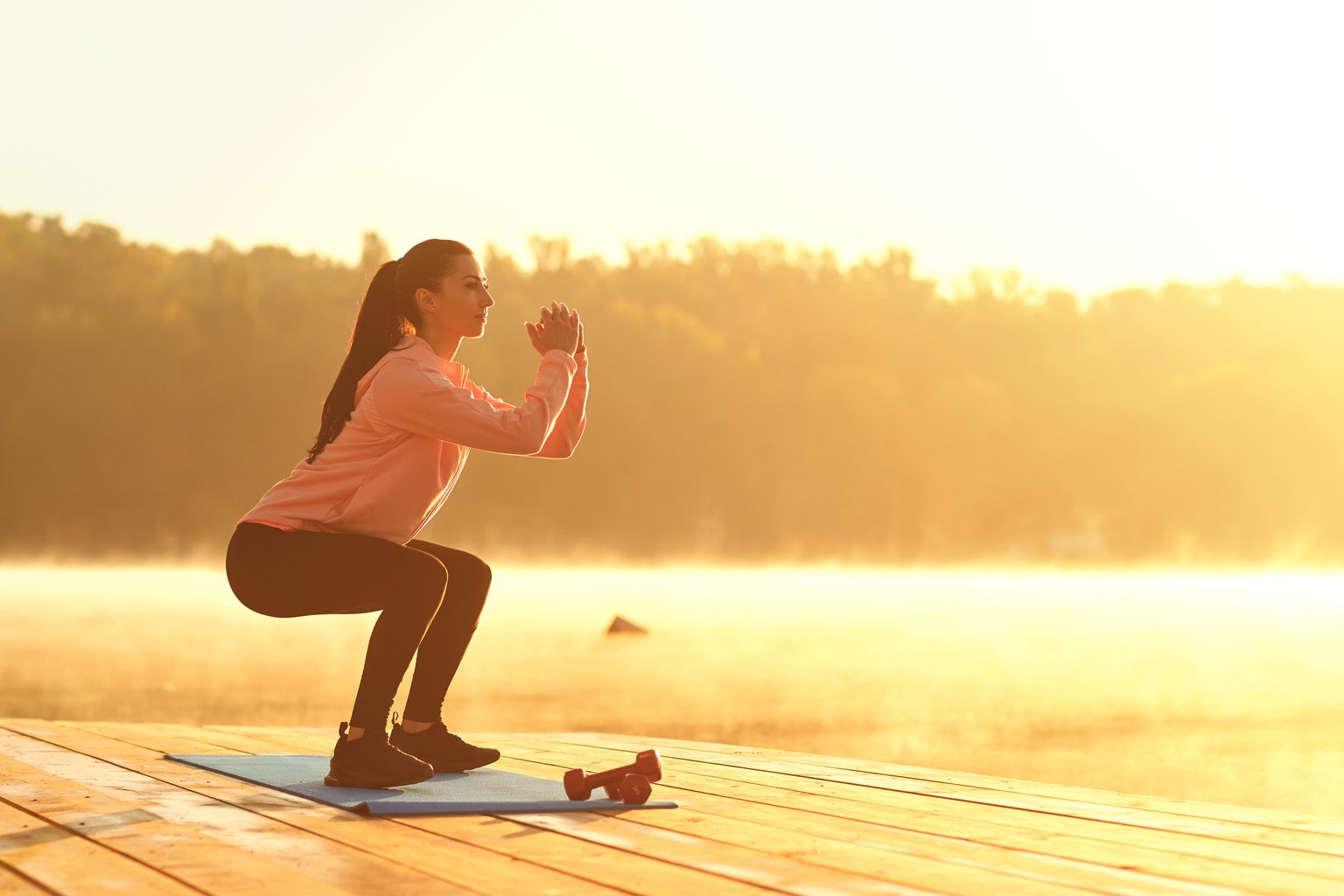 A woman doing a bodyweight squat outdoors at sunrise before her workday