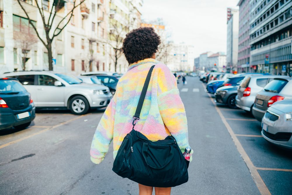 A woman walking toward the gym with a duffle bag, ready to train