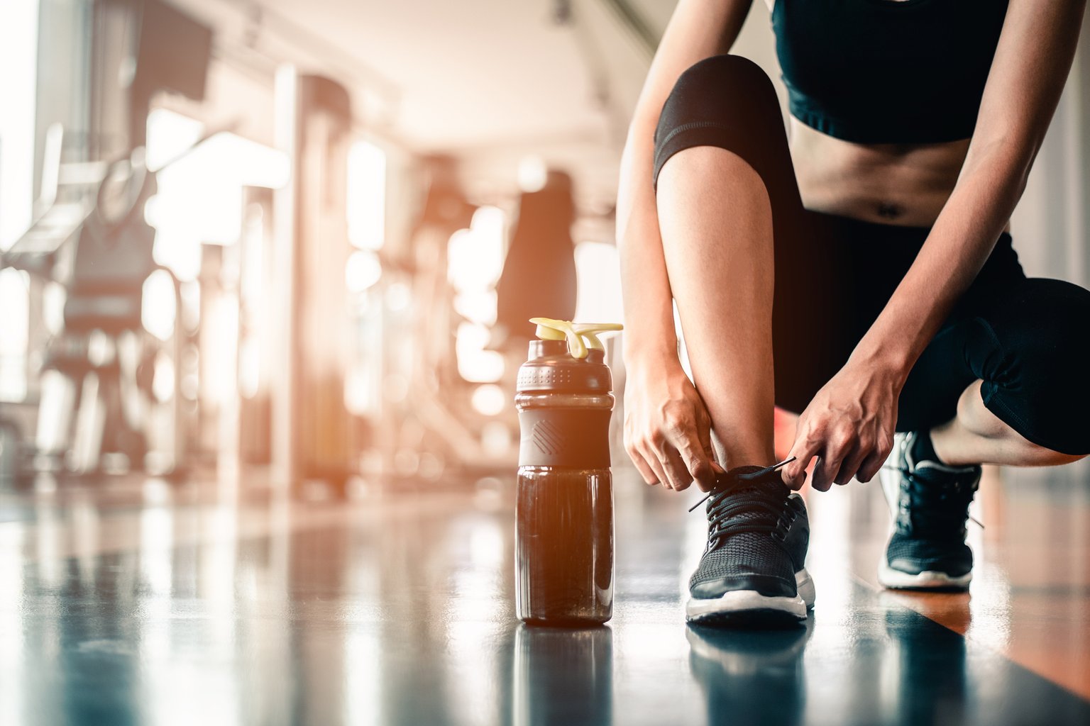 A person tying their running shoes before a workout, getting ready to show up again