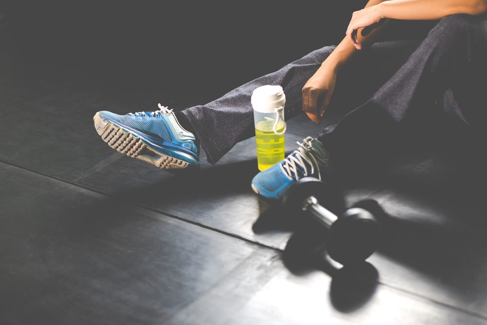 Running shoes and a dumbbell on the gym floor, ready for a comeback session