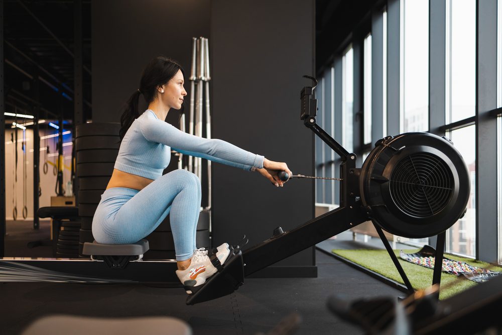A woman calmly using a rowing machine, trying an exercise at her own pace