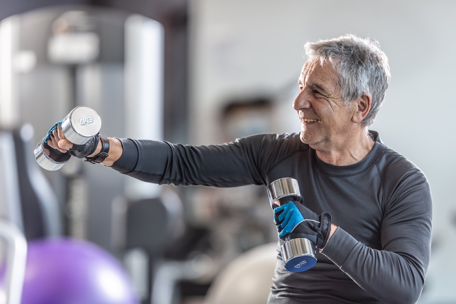 An older man performing a deadlift with a barbell in the gym, focused on form