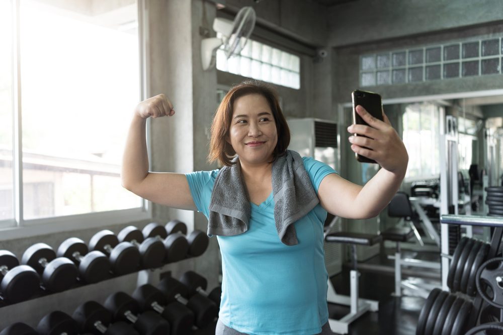 A smiling woman taking a selfie in the gym after her workout