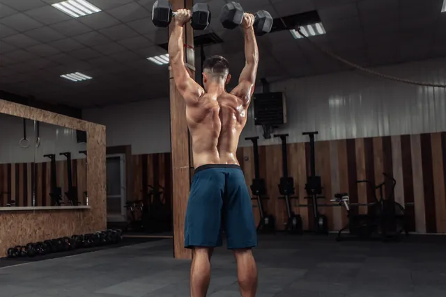 Athlete training shoulders with heavy dumbbells